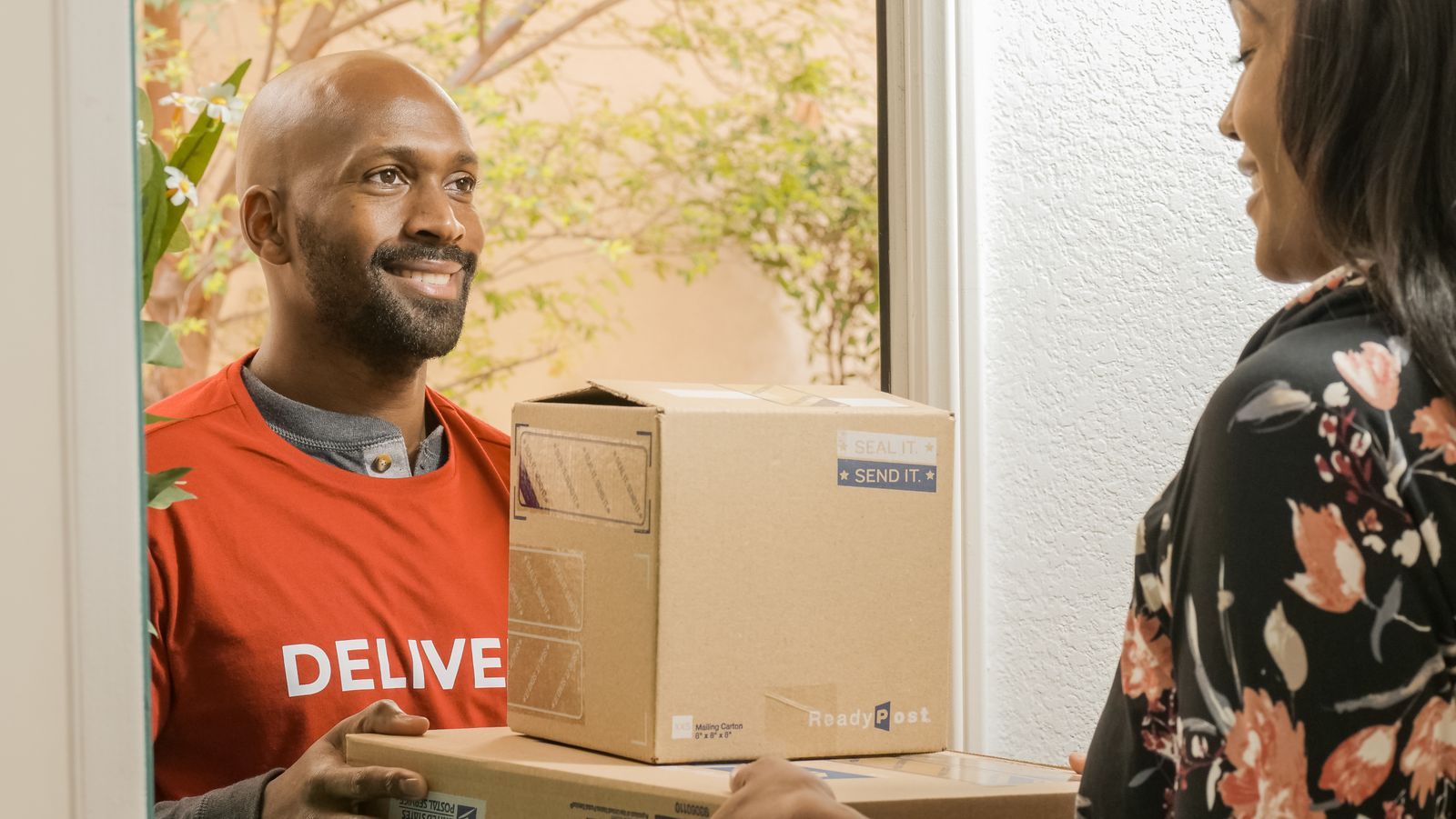 A courier handing parcels to a customer at her door