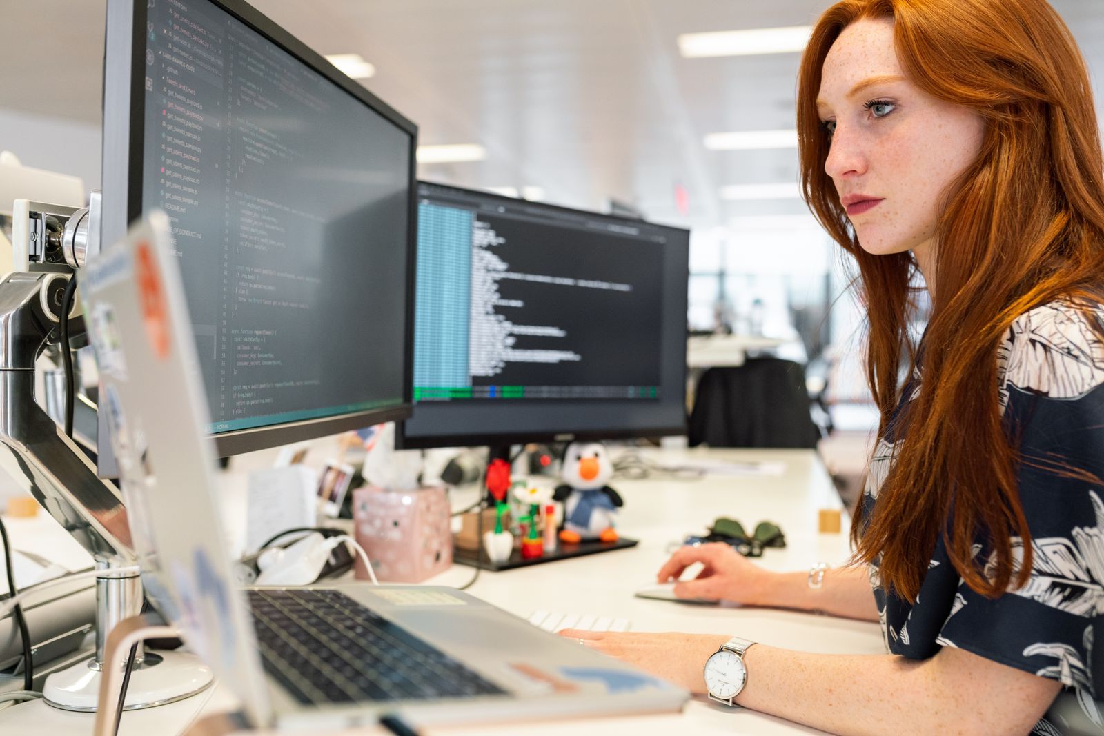 A software engineer coding at a desk with two monitors
