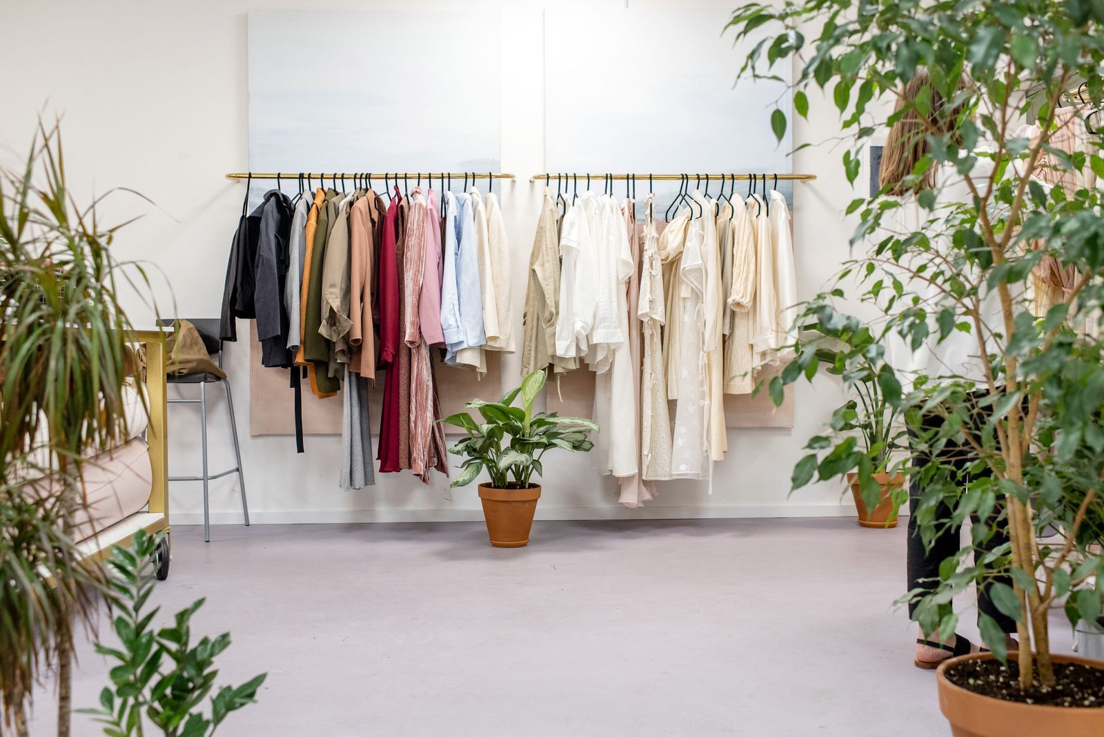 Clothing on a rail in a bright boutique with plants