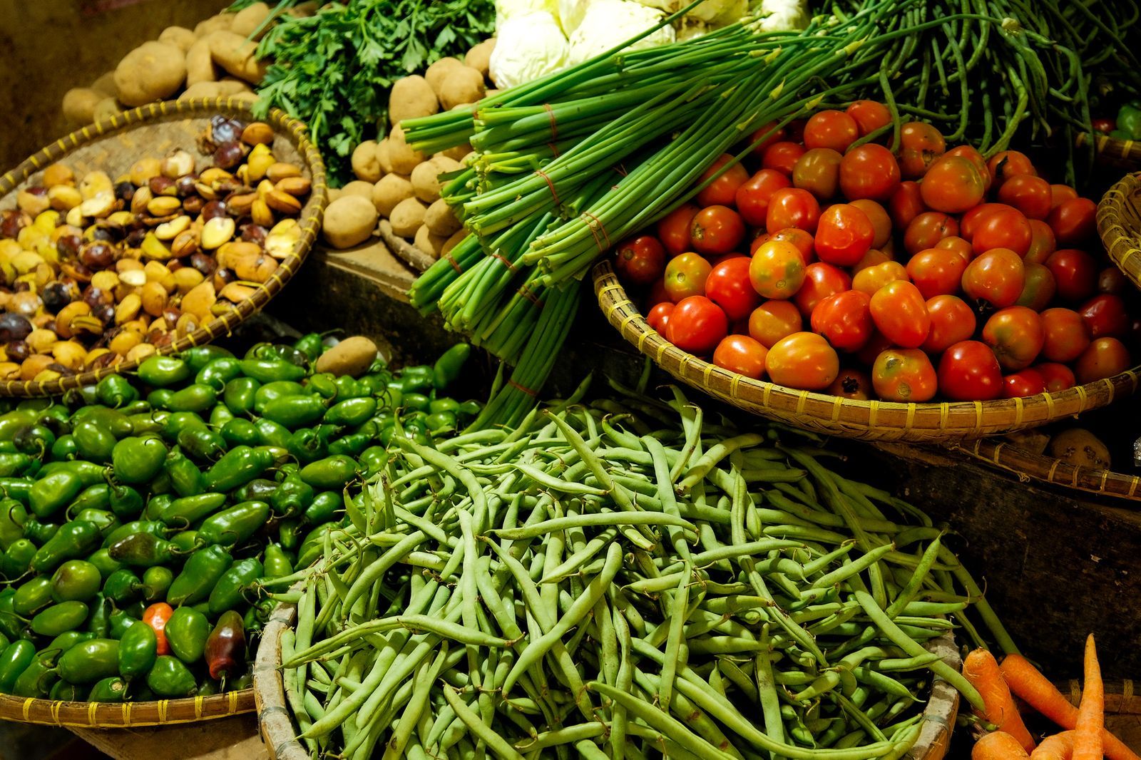 Baskets of fresh tomatoes, beans and vegetables at a market