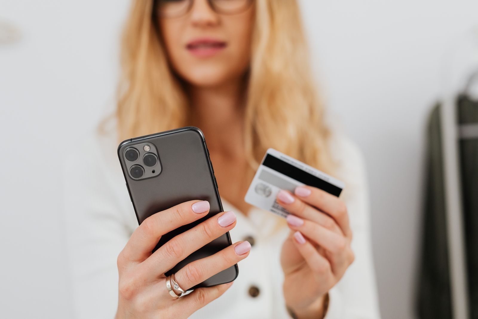A shopper holding a smartphone and a bank card to pay online
